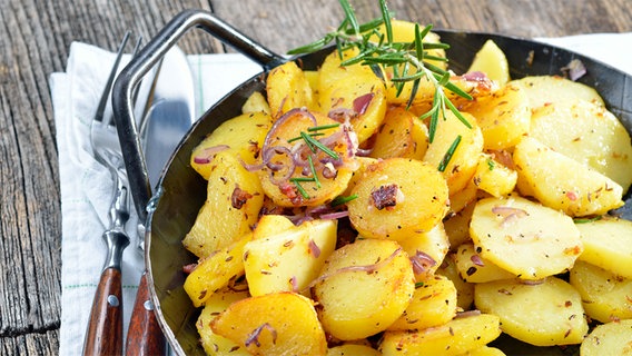 Bratkartoffeln in einer gusseisernen Pfanne, daneben Besteck auf einer Stoffserviette © kab-vision/fotolia 