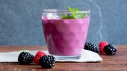 Ein Glas mit Brombeer-Shake steht auf dem Tisch, daneben liegen Brombeeren und Himbeeren. © NDR Foto: Claudia Timmann