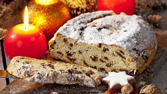 Ein angeschnittener Christstollen und weihnachtliche Kerzen © Fotolia Foto: tunedin