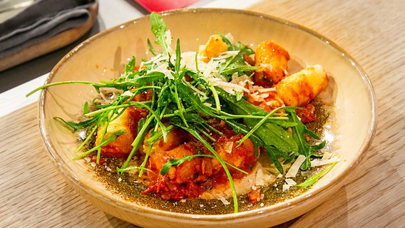 Ricotta-Gnocchi mit Tomatensoße und Rucola auf einem tiefen Teller angerichtet. © NDR/Fernsehmacher GmbH Foto: Norman Kalle