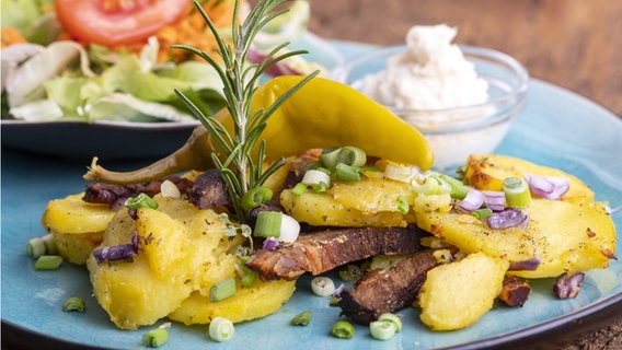 Ein Gröstl mit Kartoffeln und gebratenem Fleisch lieght auf einem Teller. © picture alliance Foto: Bernd Juergens