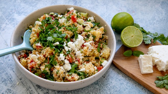 Eine Schüssel Hirse-Tabouleh, daneben Limetten, Kräuter und etwas Feta. © NDR Foto: Claudia Timmann