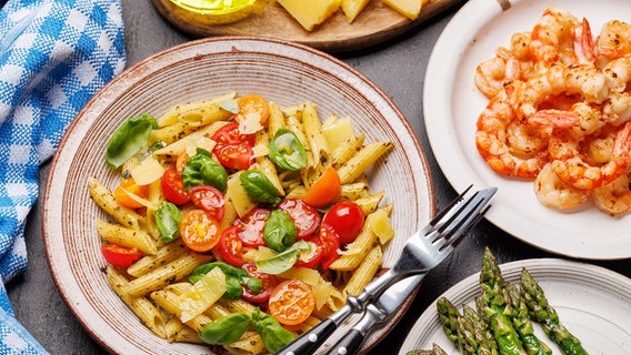 Teller mit Pasta und Tomaten sowie Basilikum, mit gebratenen Garnelen und grünem Spargel © Colourbox Foto: Evgeny Karandaev