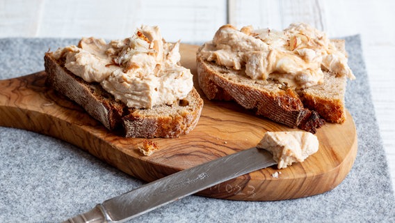 Zwei Scheiben Vollkornbrot mit Nussquark liegen auf einem Holzbrett. © NDR Foto: Claudia Timmann