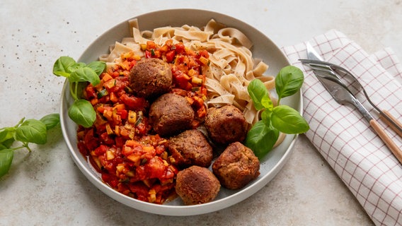 Ein Teller mit Nudeln, darauf eine Tomatensoße und Bohnenbällchen. © NDR Foto: Claudia Timmann