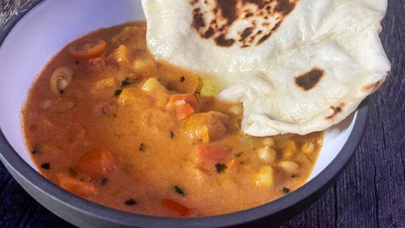 Kartoffel-Kürbis-Curry mit Naanbrot in einer Schale angerichtet © NDR 