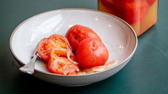 Eingekochte Tomaten auf einem hellen Teller, daneben ein Weckglas © NDR Foto: Claudia Timmann