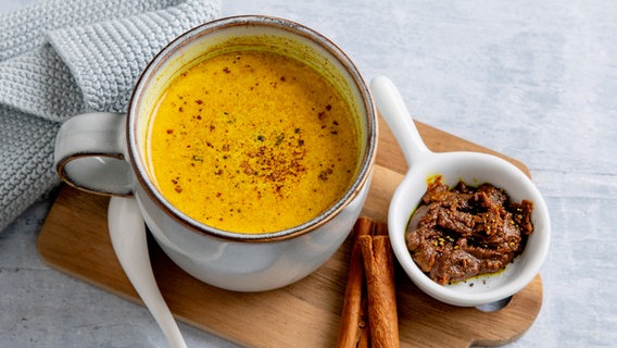 Eine Tasse mit Goldener Milch, daneben ein Schälchen Gewürzpaste. © NDR Foto: Claudia Timmann