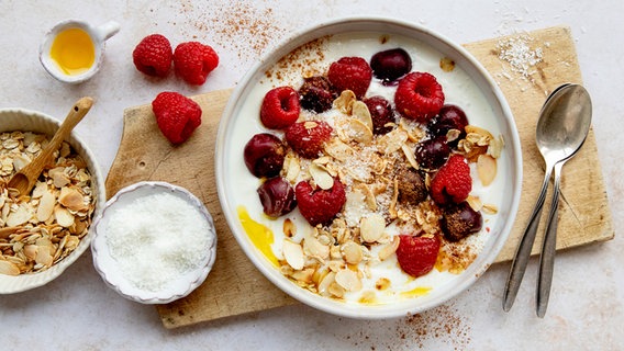 Eine flache Schüssel mit einem Joghurt, darauf Sauerkirschen und Himbeeren. © NDR Foto: Claudia Timmann