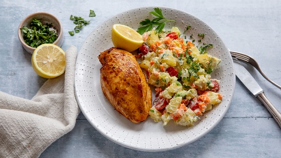 Ein Teller mit Kartoffelsalat, einer gebratenen  Hähnchenbrust und einer halben Zitrone. © NDR Foto: Claudia Timmann