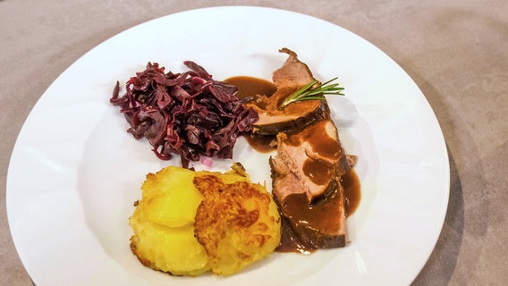 Lammkeule mit Kartoffelgratin und Rotkohl auf einem Teller serviert © NDR/Megaherz Foto: Christoph Lemmen