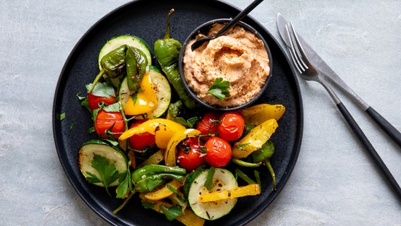 Ein Teller mit einem Ofengemüse, darauf ein Schälchen mit Hummus. © NDR Foto: Claudia Timmann