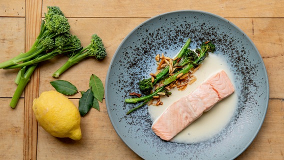 Pochierter Lachs mit Beurre blanc und Brokkoli auf einem Teller serviert © NDR Foto: Claudia Timmann