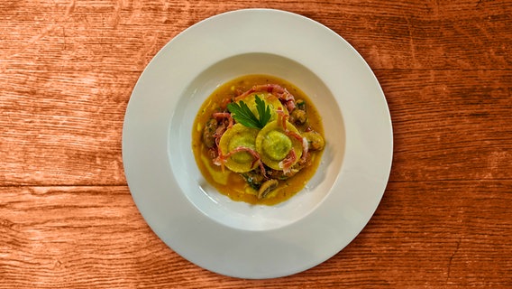 Ravioli mit Champignons, Tomate und Petersilie auf einem Teller serviert © NDR 