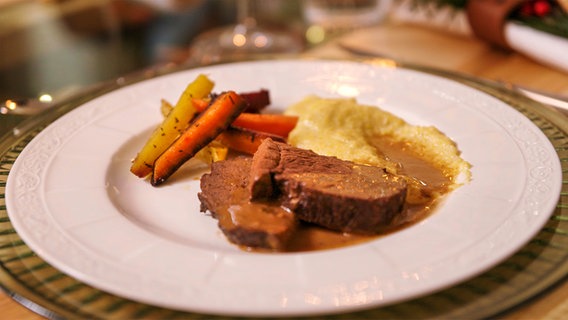 Rinderbraten mit Wurzelgemüse und Polenta auf einem Teller serviert © NDR/Megaherz Foto: Josef Mayerhofer