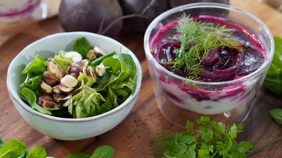 Rote-Bete-Schafskäse-Törtchen in einem Glas serviert, daneben steht eine Schale mit Feldsalat © NDR Foto: Florian Kruck