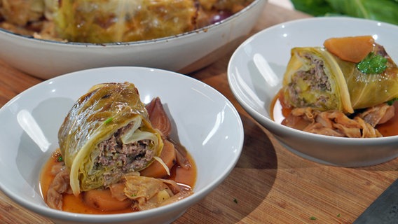 Spitzkohl-Rouladen auf Kartoffeln und Kohlgemüse in tiefen, weißen Tellern © NDR Foto: Florian Kruck