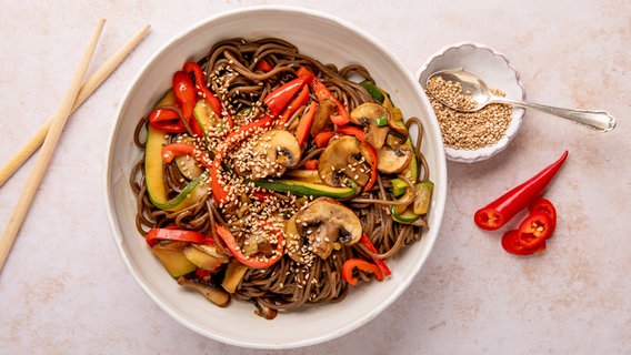 Eine Schale mit Nudeln, darauf Champignons und anderes Gemüse sowie Sesamkörner. © NDR Foto: Claudia Timmann