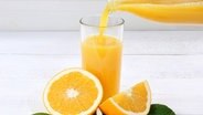 Orangensaft wird in ein Glas gegossen © imago images / Shotshop 