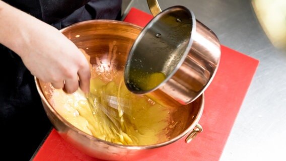Geschmolzene Butter wird in die Basis für eine Hollandaise-Soße eingerührt. © NDR Foto: Claudia Timmann