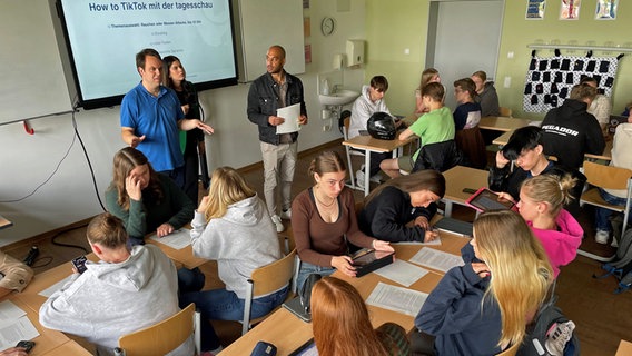 Felix Edeha und Patrick Weinhold stehen vor einer Klasse mit Schülerinnen und Schülern © NDR Foto: Carolin Fromm