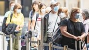 Passagiere mit Atemschutzmasken stehen in einer Warteschlange am Flughafen in Zürich. © Keystone / picture alliance Foto: Enno Leanza