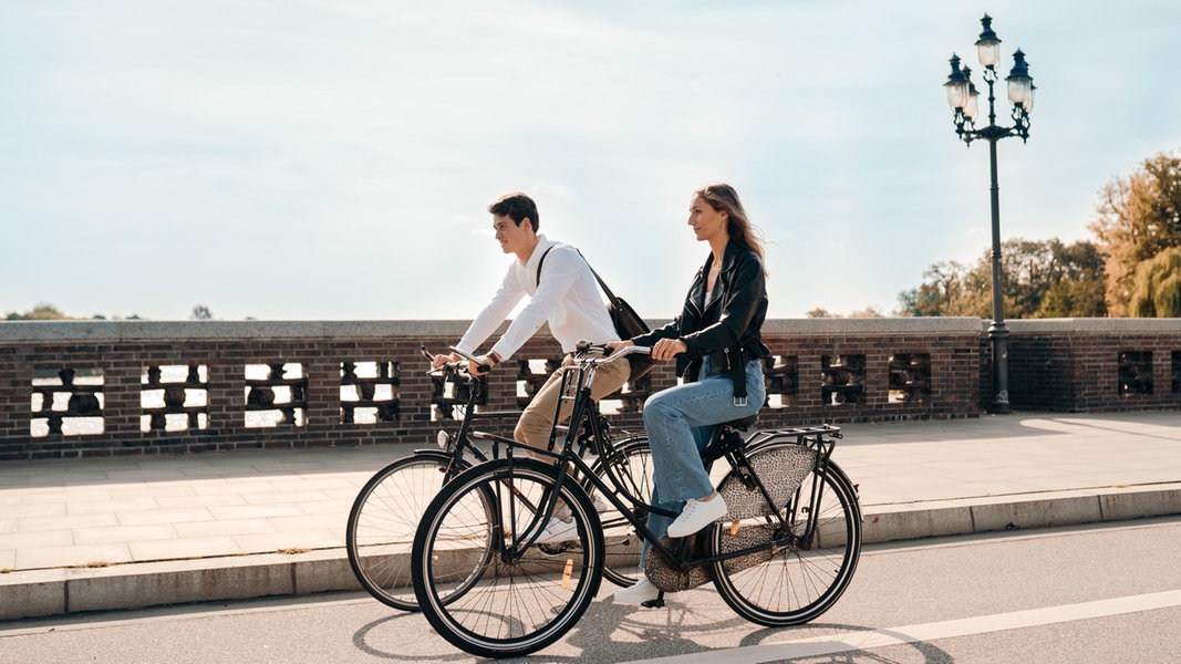 Eine Frau und ein Mann fahren mit dem Rad über eine Brücke in Hamburg.