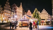 Menschen an einem weihnachtlichen Stand in der Altstadt von Lüneburg. © Lüneburg Marketing GmbH Foto: Mathias Schneider