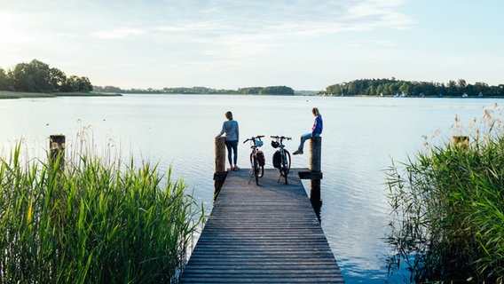 Zwei Menschen mit Fahrrädern auf einem Steg am Krakower See. © TMV Foto: Felix Gänsicke