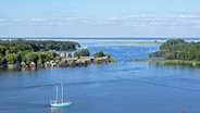 Ein Segelboot fährt bei Röbel auf der Müritz, am Ufer Bootshäuser. ©  imago/imagebroker 