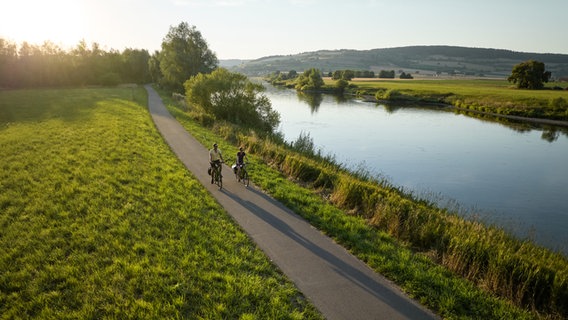 Ein Pärchen fährt auf dem Weserradweg bei Polle Fahrrad. © TourismusMarketing Niedersachsen GmbH Foto: Alexander Kaßner