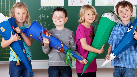 Vier Kinder vor einer Tafel mit Schultüten. © fotolia.com Foto: contrastwerkstatt