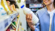 Eine junge Frau betrachtet eine Milchflasche im Supermarkt. © SydaProductions, fotolia Foto: SydaProductions