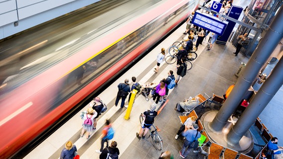 Reisende stehen auf einem Bahnsteig, auf dem ein Zug einfährt. © dpa-Bildfunk Foto: Christoph Soeder