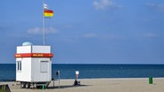 Eine rot-gelbe Flagge weht an einem DLRG-Wachhaus in Niendorf an der Ostsee. © picture alliance/Bildagentur online Foto: Ohde