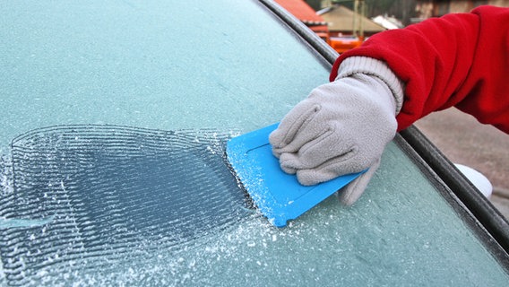 Jemand kratzt die Frontscheibe seines Autos mit einem Eiskratzer. © picture alliance Foto: Fleig / Eibner-Pressefoto