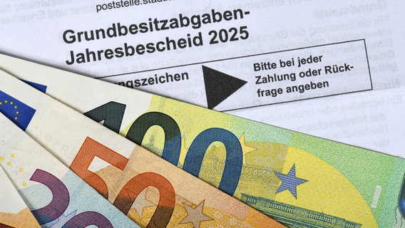 "Grundbesitzabgaben-Jahressteuerbescheid 2025" ist auf einem offiziellen Schreiben zu lesen, darunter liegen mehrere Geldscheine. © picture alliance / imageBROKER | Michael Weber Foto: Michael Weber