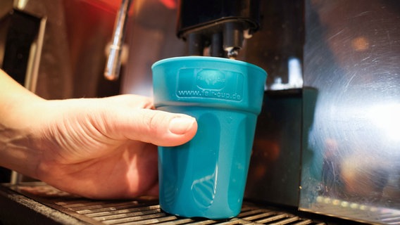 Ein Kunde füllt einen wiederverwendbaren Getränkebecher an einem Kaffeautomaten auf. © dpa-Bildfunk Foto: Christian Charisius