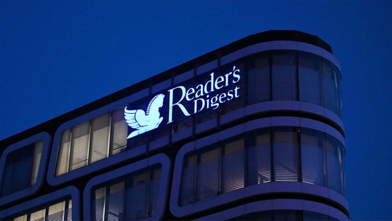 Der Schriftzug "Reader's Digest" leuchtet auf dem Verlagsgebäude in Stuttgart bei Nacht. © picture alliance / ZUMAPRESS.com | Ryan Remiorz 