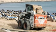 Bauarbeiten an einem Badestrand auf Fuerteventura: Im Vordergrund ein Bagger, im Hintergrund leere Liegen. © picture alliance / Caro | Sorge 