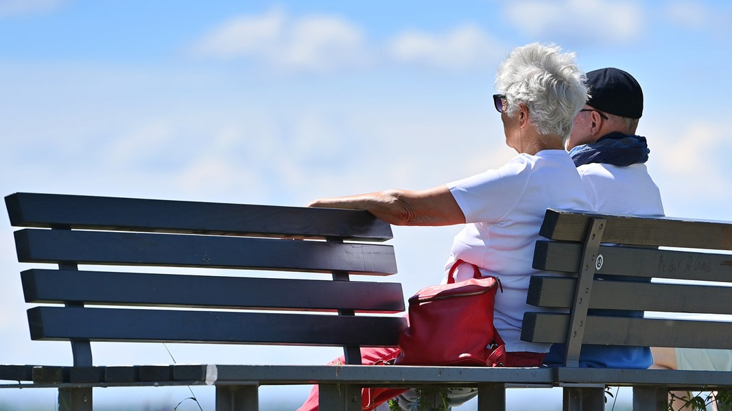 Ein Rentnerpaar sitzt auf einer Bank. 