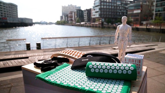 Mehrere Hilfsmittel gegen Rückenschmerzen liegen auf einem Tisch in der Hamburger Hafencity. © NDR 
