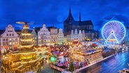 Blick auf den Rostocker Weihnachtsmarkt mit Riesenrad und Pyramide © imago images Foto: IMAGO / Marc Stinger