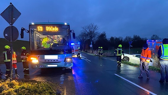 Ein Schulbus steht im Dunkeln an einer Landstraße, Einsatzkräfte laufen herum, ein Wagen liegt in einem Graben © Polizeiinspektion Cuxhaven 