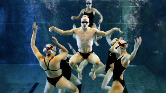 Ein Mann mit Nasenklammer, Pailletten auf der Badehose und Gelantine im Haar, sehr lange war das höchsten Stoff für Kino-Komödien. Für Männer war bis 2015 international Synchronschwimmen nicht erlaubt. Frithjof Seidel ist einer der ganz wenigen Männer, die sich in diese Frauen-Domäne gewagt haben und erfolgreich sind. Der ehemalige Wasserspringer musste alles ganz neu erlernen, trainierte mit kleinen Mädchen als völliger Anfänger. © Deutsche Welle (Drehmaterial) 