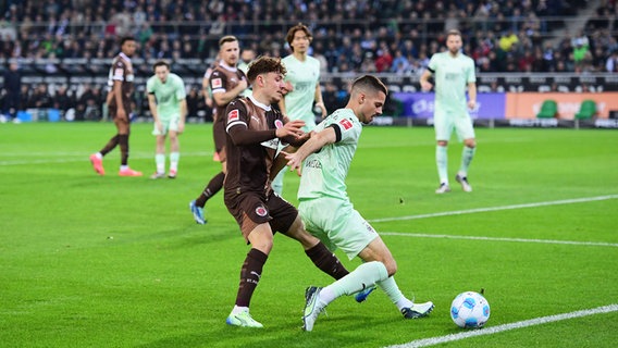 St. Paulis Philipp Treu (l.) und Gladbachs Julian Weigl kämpfen um den Ball. © IMAGO / fohlenfoto 