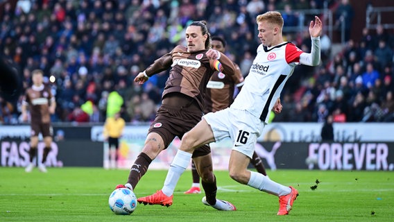 St. Paulis Kapitän Jackson Irvine (l.) und Frankfurts Hugo Larsson kämpfen um den Ball. © Witters/LeonieHorky 