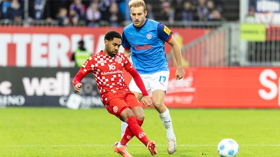 Kiels Timo Becker und der Mainzer Philipp Mwene kämpfen um den Ball. © picture alliance/dpa | Axel Heimken 