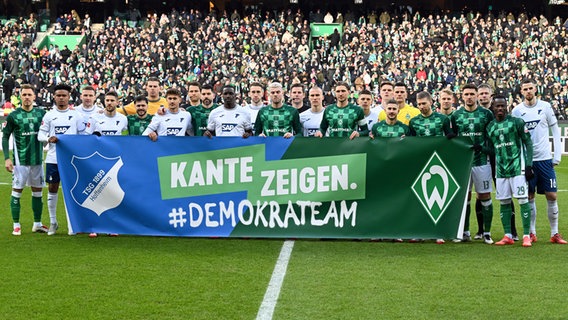 Die Spieler Bremens (grün) und Hoffenheims hinter einem Spruchband mitd er Aufschrift "Kante zeigen. #demokrateam" © picture alliance / DPA 