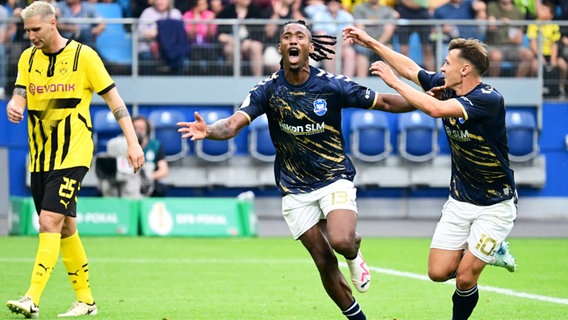 Obinna Iloka (M.) und Jonathan Stöver von Phönix Lübeck bejubeln einen Treffer. © IMAGO / KBS-Picture 